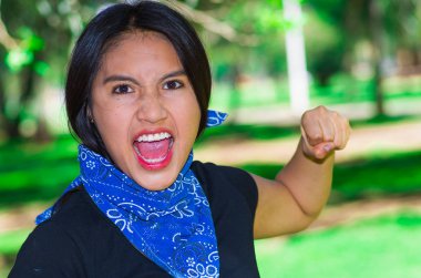 Açık havada kamera için aktivist protesto kavramı etkileşim boynuna, mavi bandana giyen genç esmer kadın