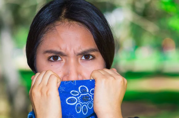 Mujer morena joven con bandana azul cubriendo la mitad de la cara, interactuando al aire libre para la cámara, concepto de protesta activista — Foto de Stock