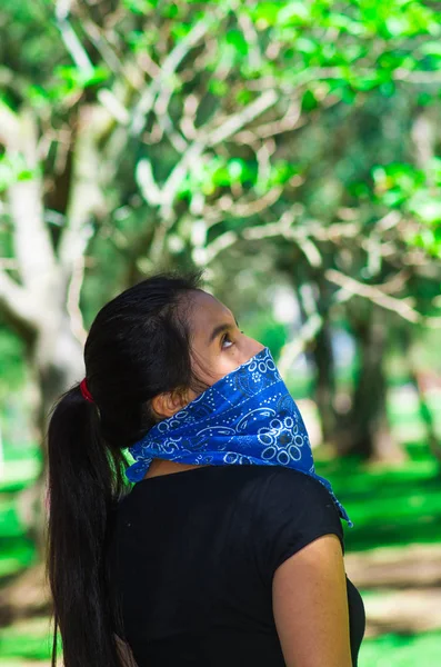 Mujer morena joven con bandana azul cubriendo la mitad de la cara, interactuando al aire libre para la cámara, concepto de protesta activista — Foto de Stock