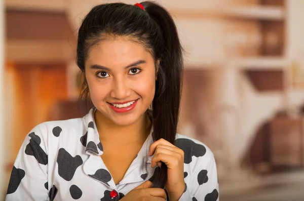 Young brunette woman posing in pyjamas, holding hair and smiling to camera — Stock Photo, Image