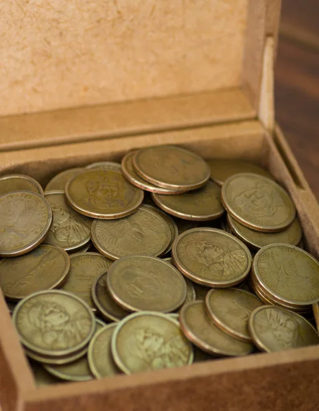 Close up brown box filled with dollar coins — Stock Photo, Image