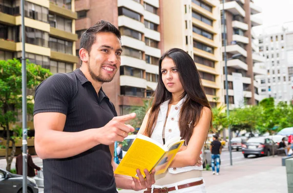 Charmante jonge paar staan buiten in stedelijke omgeving, holding open boek en interactie, stedelijke toeristische concept — Stockfoto