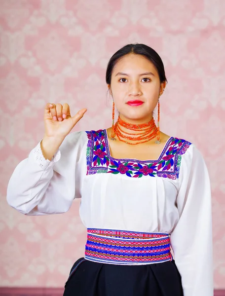 Jonge vrouw dragen traditionele Andes jurk, geconfronteerd met camera doen gebarentaal woord voor hello — Stockfoto