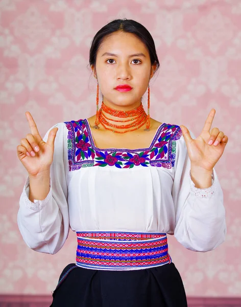Ung kvinna bär traditionella andinska klänning, inför kameran gör teckenspråk ordet för frihet — Stockfoto