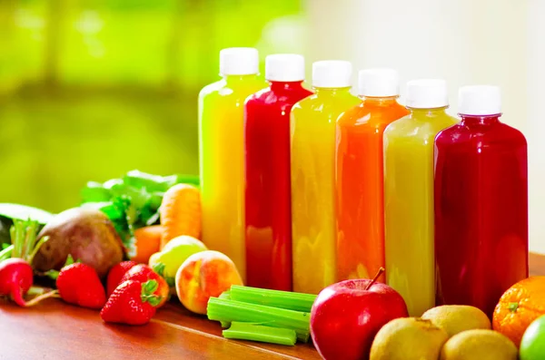 Seis botellas de delicioso jugo orgánico de pie en una fila rodeada de frutas y verduras, hermosos colores —  Fotos de Stock