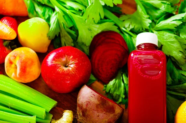 Botellas de delicioso jugo orgánico en el escritorio rodeado de frutas y verduras, hermosos colores, concepto de estilo de vida saludable —  Fotos de Stock