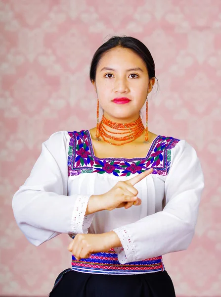 Ung kvinna bär traditionella andinska klänning, inför kameran gör teckenspråk ordet för restroom — Stockfoto