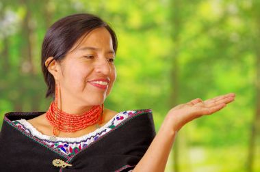 Tatlı güzel İspanyol kadın giyiyor geleneksel and beyaz bluz boyun, siyah panço, eşleşen kırmızı kolye ve kulak, mutlu bir şekilde poz için fotoğraf makinesi, Bahçe arka plan etrafında renkli dekorasyon ile