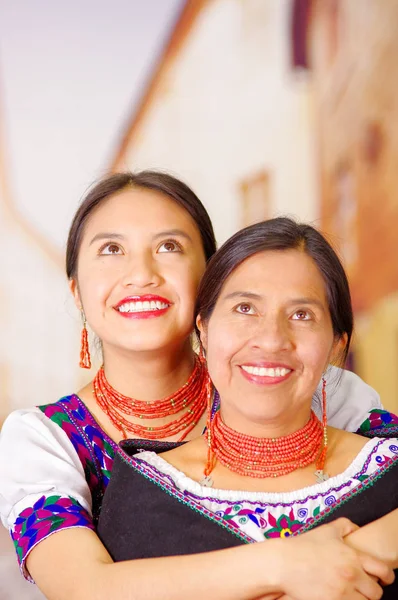 Belo retrato de mãe com filha, ambos vestindo roupas tradicionais andinas e colares combinando, posando abraçando alegremente — Fotografia de Stock