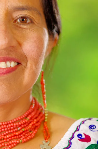Feche a bela mulher hispânica vestindo blusa branca andina tradicional com decoração colorida ao redor do pescoço, combinando colar vermelho e orelha, posando feliz para câmera, fundo do jardim — Fotografia de Stock