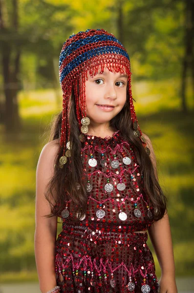 Schattig klein meisje mooie rode jurk met bijpassende parel hoed te dragen, te poseren voor de camera, groene bos achtergrond — Stockfoto