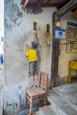 George Town şehir merkezinde, Malezya bir sandalye üzerinde duran çocuk sokak sanatı grafiti.