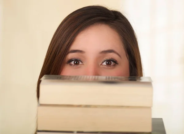 Jonge mooie vrouw verstopt achter een boek — Stockfoto