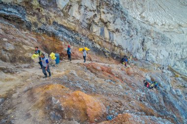 Kaweh Ijen'de, Endonezya - 3 Mart, 2017: Yerel madenciler dağ tarafı yukarı sarı sülfür kayaçların ağır sepetleri taşıyan, turistik cazibe hiking bulunan volkanik krater, muhteşem doğa içinde