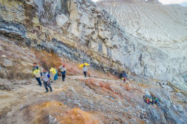 Kaweh Ijen'de, Endonezya - 3 Mart, 2017: Yerel madenciler dağ tarafı yukarı sarı sülfür kayaçların ağır sepetleri taşıyan, turistik cazibe hiking bulunan volkanik krater, muhteşem doğa içinde