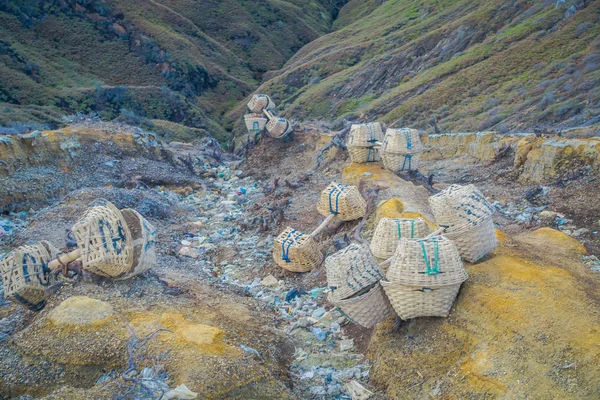 Ijen Antal, Indonézia: Kosarak, használt kén sziklák bánya fekvő szétszórva a földön, nagy magasságban vulkanikus táj — Stock Fotó