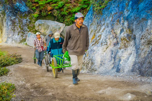 KAWEH IJEN, INDONÉSIA - 3 DE MARÇO DE 2017: Mineiros locais usando carrinhos de mão para transportar enxofre e equipamentos da mina localizados dentro da cratera vulcânica, paisagem de alta altitude — Fotografia de Stock