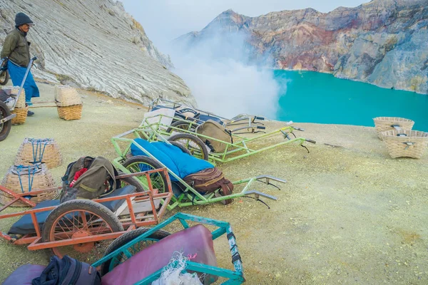 KAWEH IJEN, INDONESIA - 3 MARCH, 2017: Local miners using wheelbarrows to transport sulfur and equipment from mine located inside volcanic crater, high altitude landscape — Stock Photo, Image