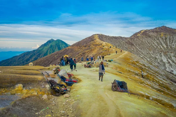 Kaweh Ijen，印度尼西亚-2017 年 3 月 3 日︰ 当地矿工驮黄色硫磺岩石山的另一边了，旅游远足吸引力位于火山的火山口，壮观的大自然 — 图库照片