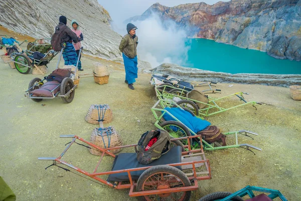KAWEH IJEN, INDONESIA - 3 MARCH, 2017: Local miners using wheelbarrows to transport sulfur and equipment from mine located inside volcanic crater, high altitude landscape — Stock Photo, Image