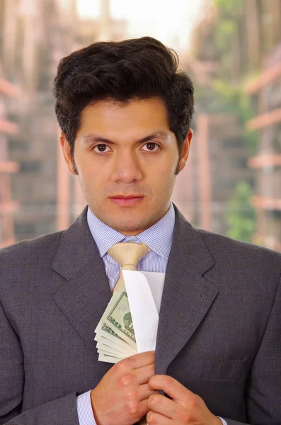 Uomo d'affari in abito scuro e con cravatta mettere soldi nel suo vestito — Foto Stock