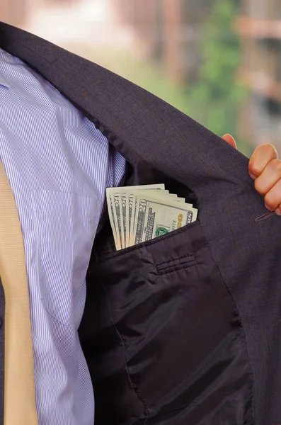 Businessman in dark suit and with tie putting money in his pocket — Stock Photo, Image