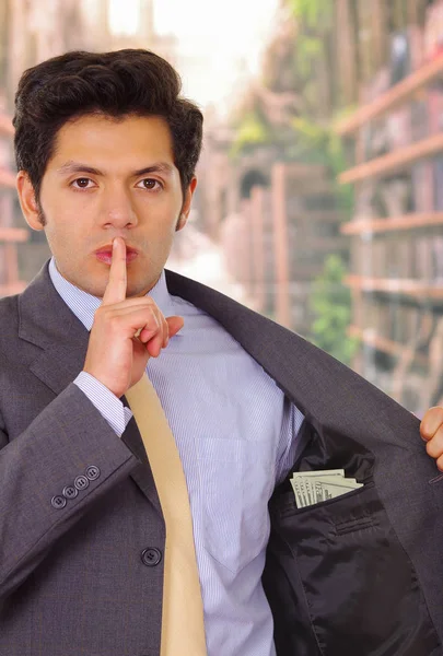Empresário em terno escuro e com gravata colocando dinheiro em seu bolso — Fotografia de Stock