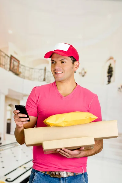 Delivery man in pink uniform holding boxes and documents. — Stock Photo, Image