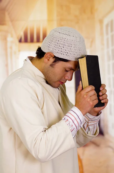 Carino giovane ragazzo arabo che prega Dio con un libro sacro in mano — Foto Stock