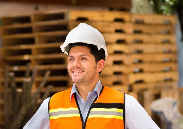 Инженер смотрит в сторону, держа планшет на строительной площадке — стоковое фото