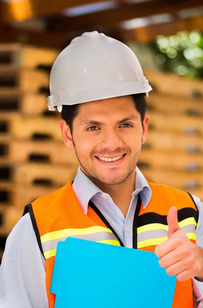 Улыбающийся молодой инженер держит папку на стройке — стоковое фото