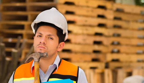 Handsome young engineer holding a folder and hammer in his jaw — Stock Photo, Image