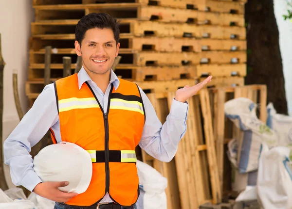 Smiling engineer with a helmet in his hand at construction site — Stock Photo, Image