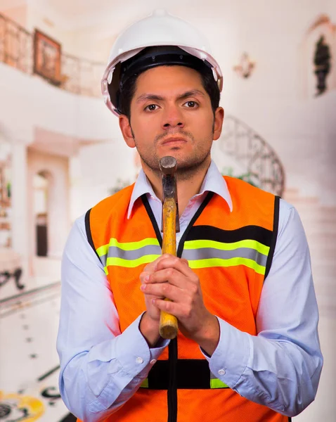 Handsome young engineer holding a folder and hammer in his jaw — Stock Photo, Image