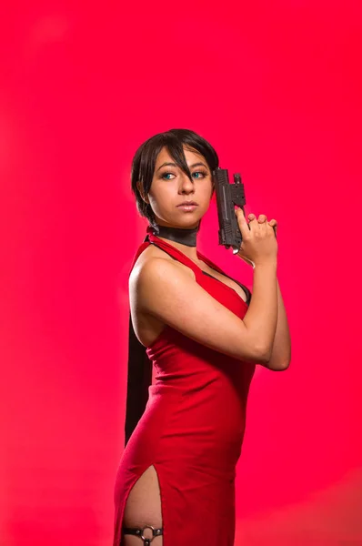 Могущественная женщина позирует с пистолетом в лице, ada wong cosplay — стоковое фото