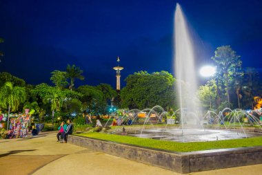 Banyuwangi, Endonezya: yeşil bitki örtüsü ve popüler su çeşme, zevk insanlar, güzel mavi akşam gökyüzü arka planda ile park alanı büyüleyici