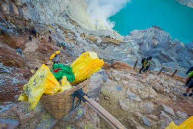Kaweh Ijen'de, Endonezya: Sarı sülfür kayalar sepetleri, muhteşem volkanik krater Gölü arka plan, turistik cazibe hiking içinde