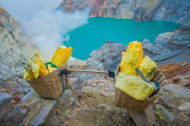 Kaweh Ijen'de, Endonezya: Sarı sülfür kayalar sepetleri, muhteşem volkanik krater Gölü arka plan, turistik cazibe hiking içinde