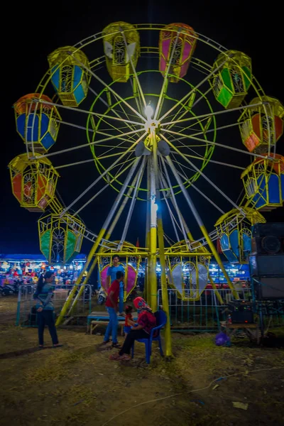 BANYUWANGI, INDONÉSIA: Locais vistos brincando na frente de uma pequena roda gigante, localizada dentro da encantadora área do parque, fundo do céu noturno — Fotografia de Stock