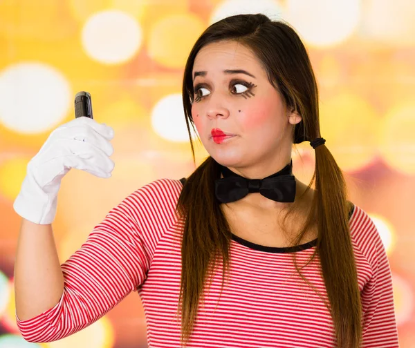 Closeup portrait of cute young girl clown mime holding cell phone — Stock Photo, Image