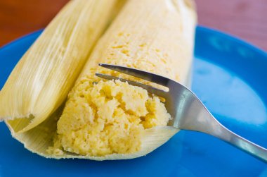 Üzerinde mavi bir tabak humita bir parça Dilimleme metalik çatal