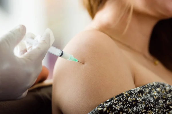 Verpleegster met spuit maken een injectie aan de schouder van een dames — Stockfoto
