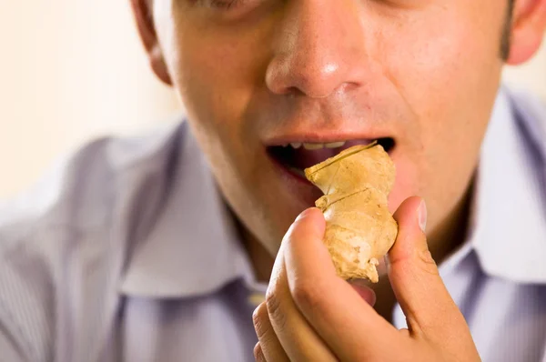 Schöner junger Mann isst gern ein Stück Ingwer — Stockfoto