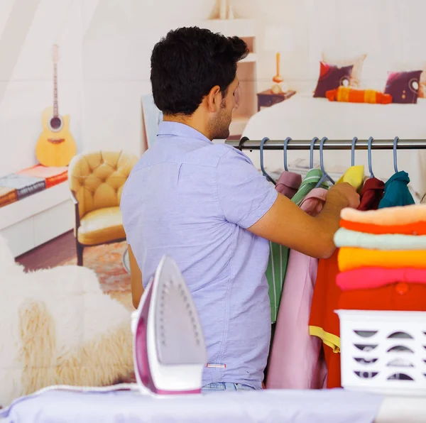 Hombre joven guapo ordenar después de planchar ropa en la tabla de planchar — Foto de Stock