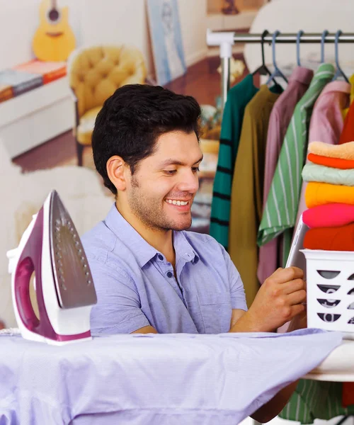 Handsome young Man tidy up after Ironing Clothes On Ironing Board