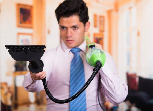 Handsome young Man cleaning home with vacuum cleaner in his shoulder — Stock Photo, Image