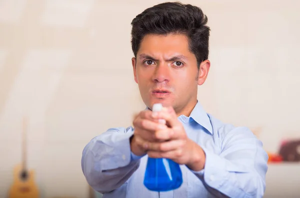 Schöner junger kaukasischer Mann zeigt Putzsprayflasche vor sich — Stockfoto