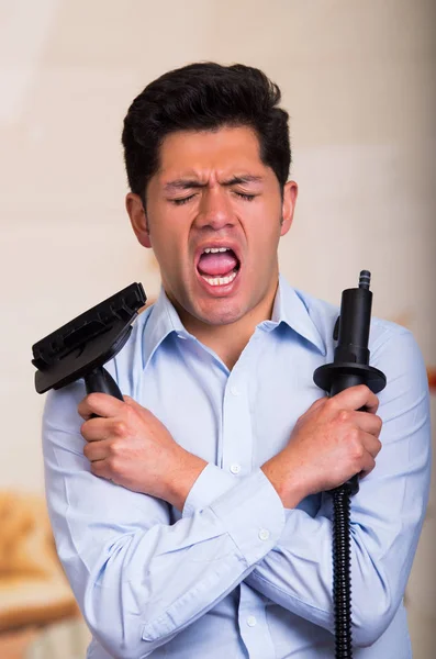 Handsome young Man holding a vacuum cleaner while he put a silly face — Stock Photo, Image