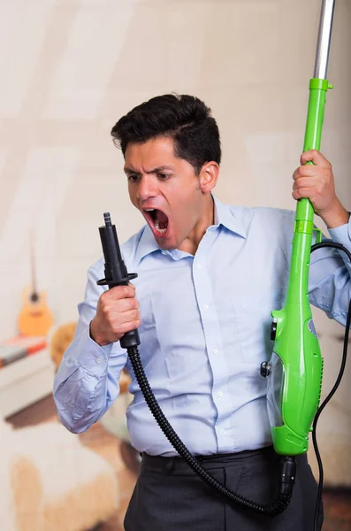 Knappe jonge Man houden een stofzuiger en schreeuwen — Stockfoto
