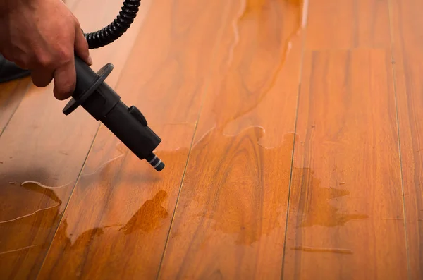 Чистая вода на деревянном полу с пылесосом — стоковое фото